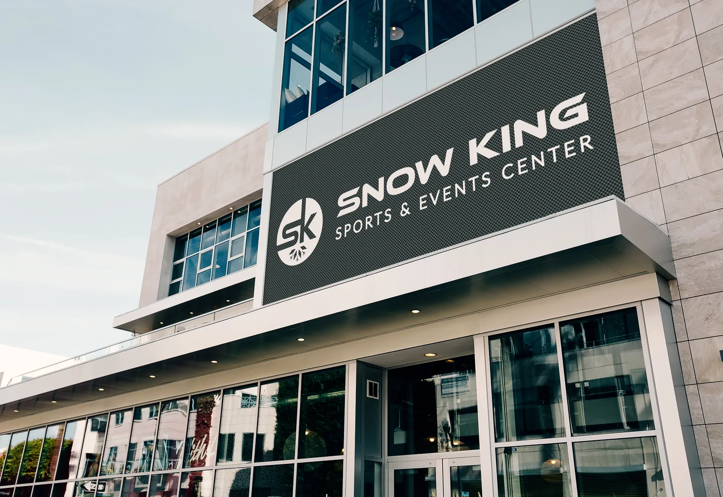 Concept mockup: the Snow King Sports & Events Center emblem and name on a building sign.