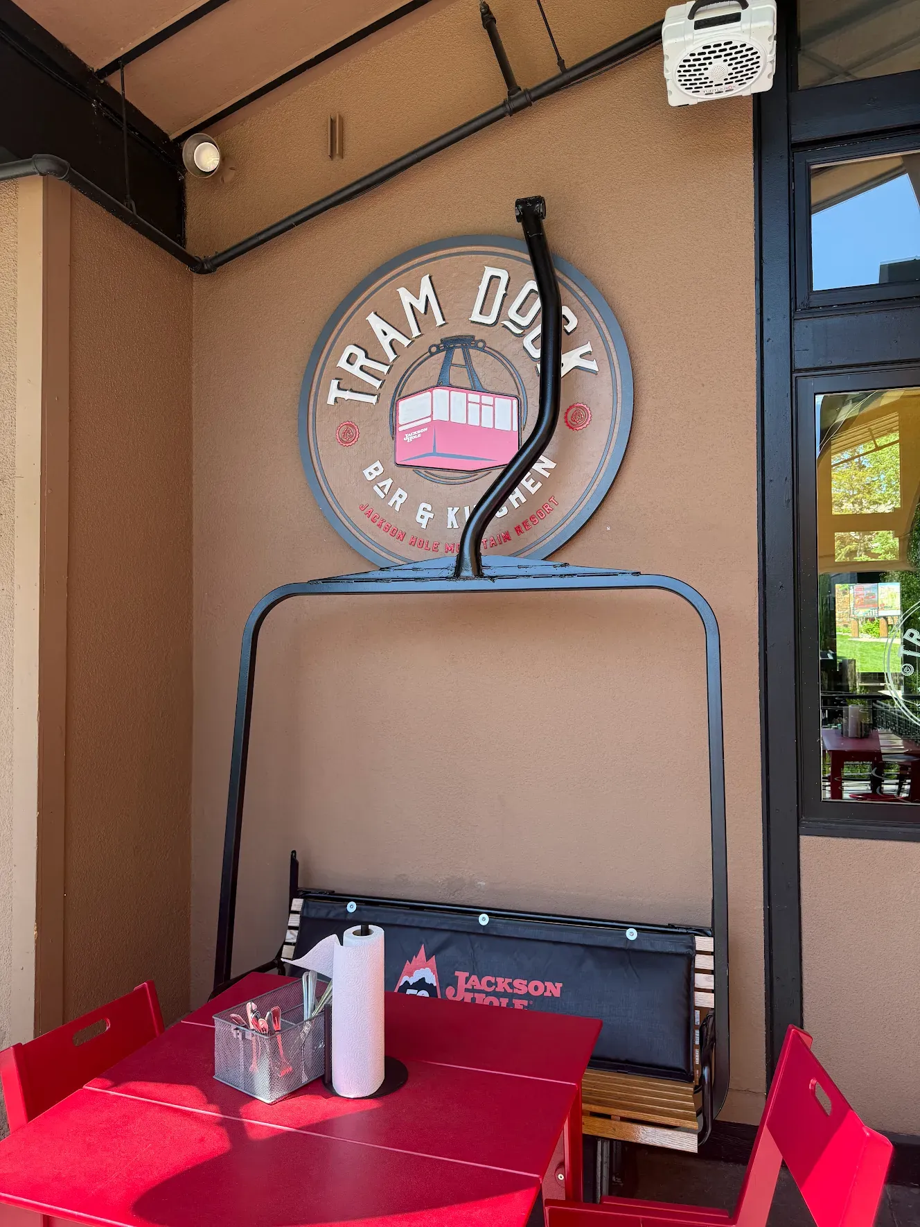 The Tram Dock badge on a patio wall, above a bench made from a chairlift chair.